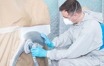 woman on phone looking at car damage