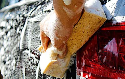 woman on phone looking at car damage