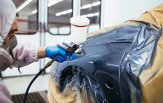 woman on phone looking at car damage