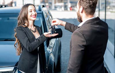 woman on phone looking at car damage